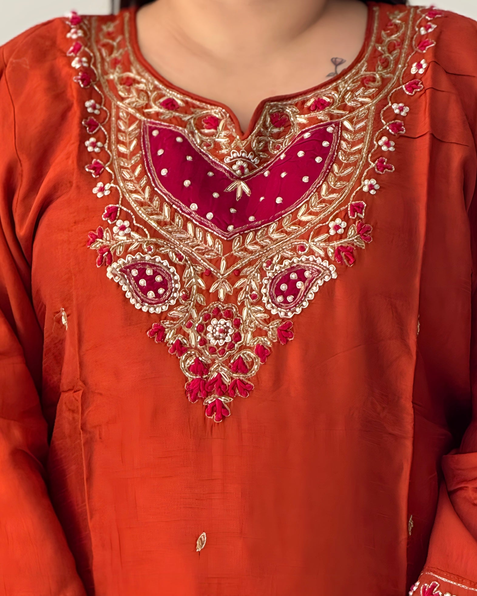 Close-up of a red embroidered garment with gold and white details.