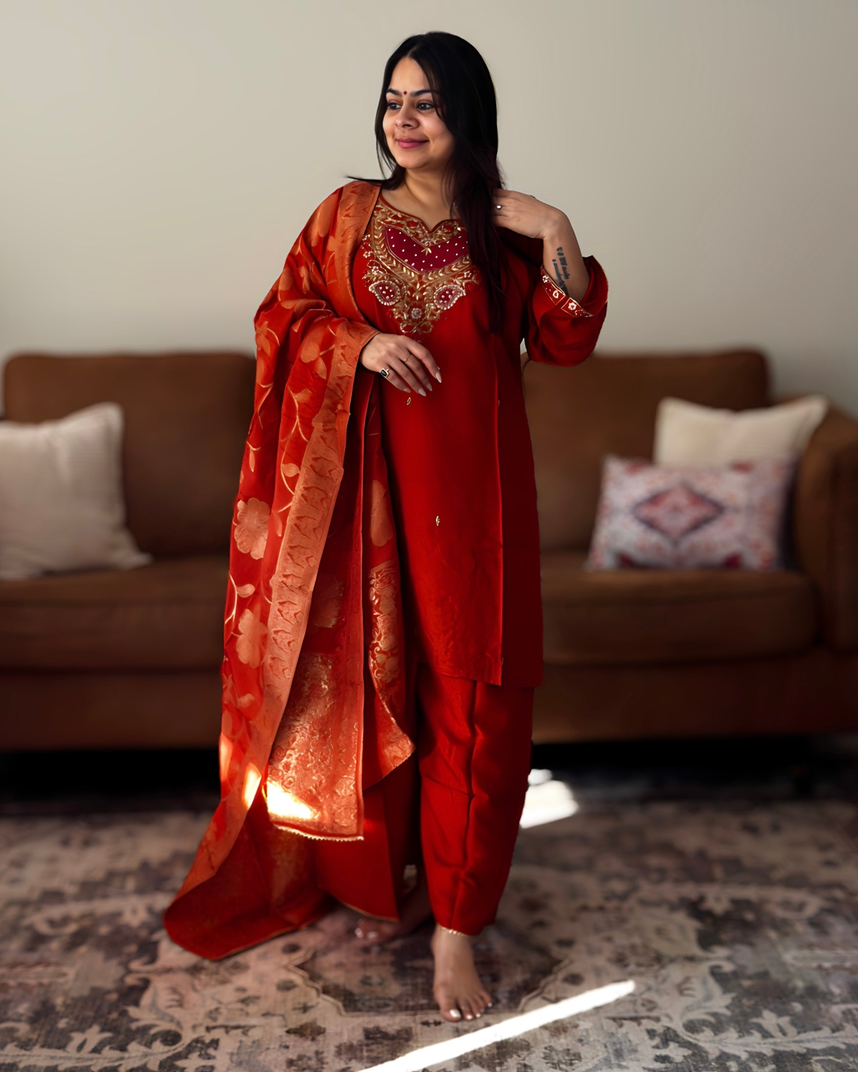 Woman in a red traditional outfit standing in a living room.
