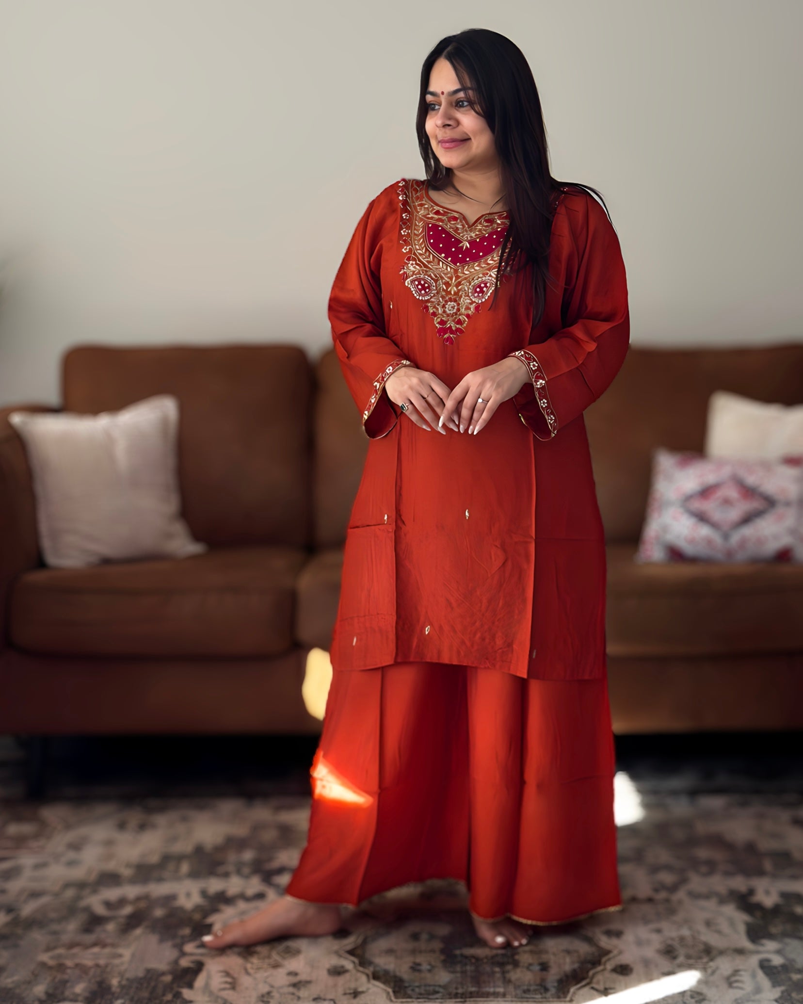 Woman in a red traditional outfit standing in a living room.