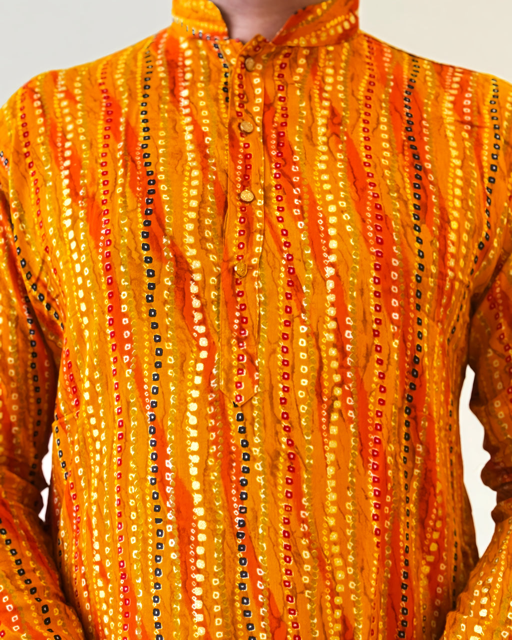 Orange and yellow patterned garment with a hood on a plain background