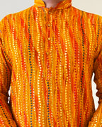 Orange and yellow patterned garment with a hood on a plain background