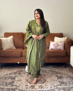 Woman in a green traditional outfit standing in a living room.