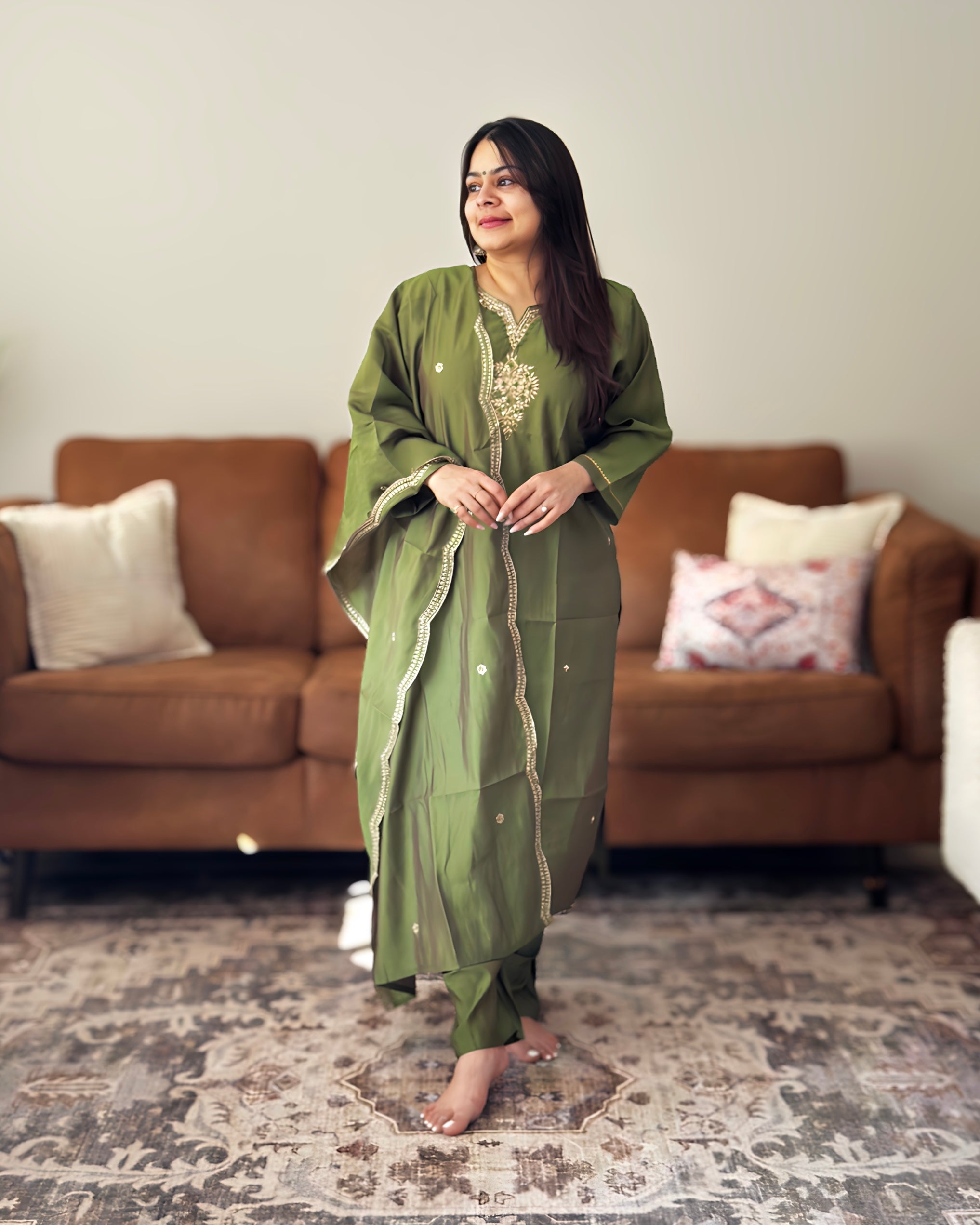 Woman in a green traditional outfit standing in a living room.
