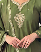 Green embroidered garment with intricate patterns on a plain background