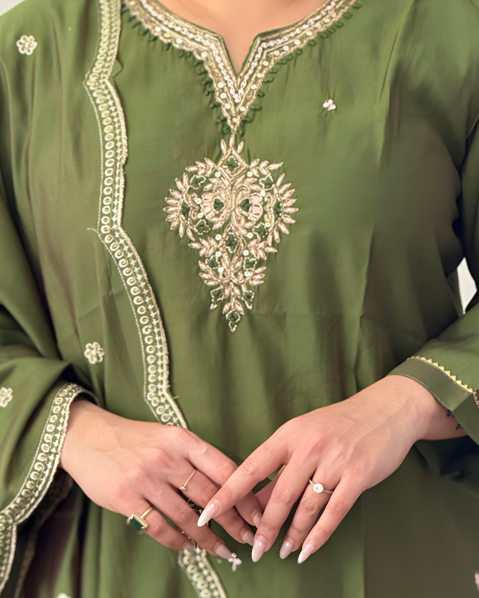 Green embroidered garment with intricate patterns on a plain background