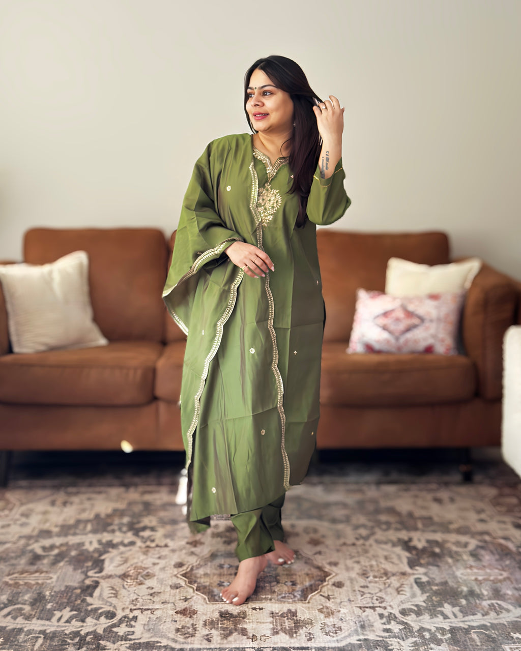 Woman in a green traditional outfit standing in a living room.