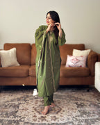 Woman in a green traditional outfit standing in a living room.