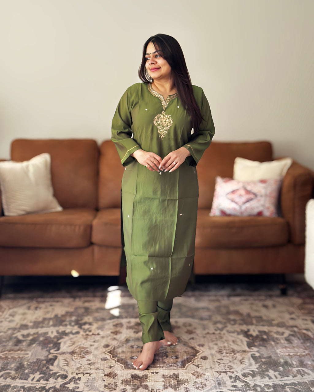 Woman in a green traditional outfit standing in a living room.