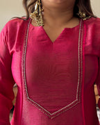 A close-up of a person wearing a bright pink traditional tunic top with gold embroidered trim along the neckline and a matching sheer pink dupatta draped over the shoulders.