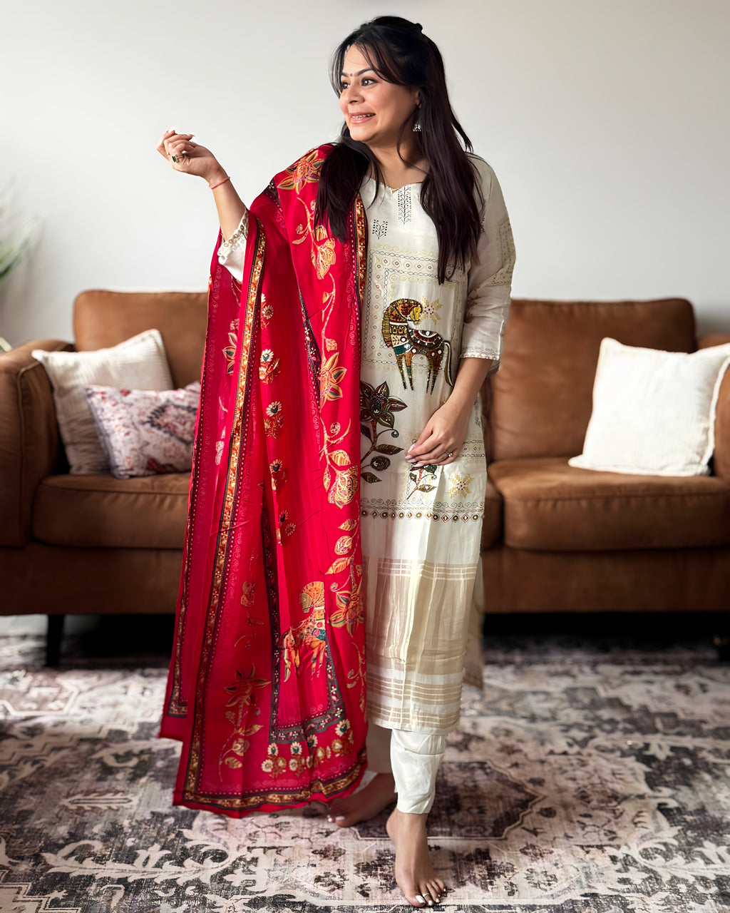 Woman holding a red embroidered dupatta in a living room setting