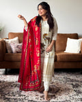 Woman holding a red embroidered dupatta in a living room setting