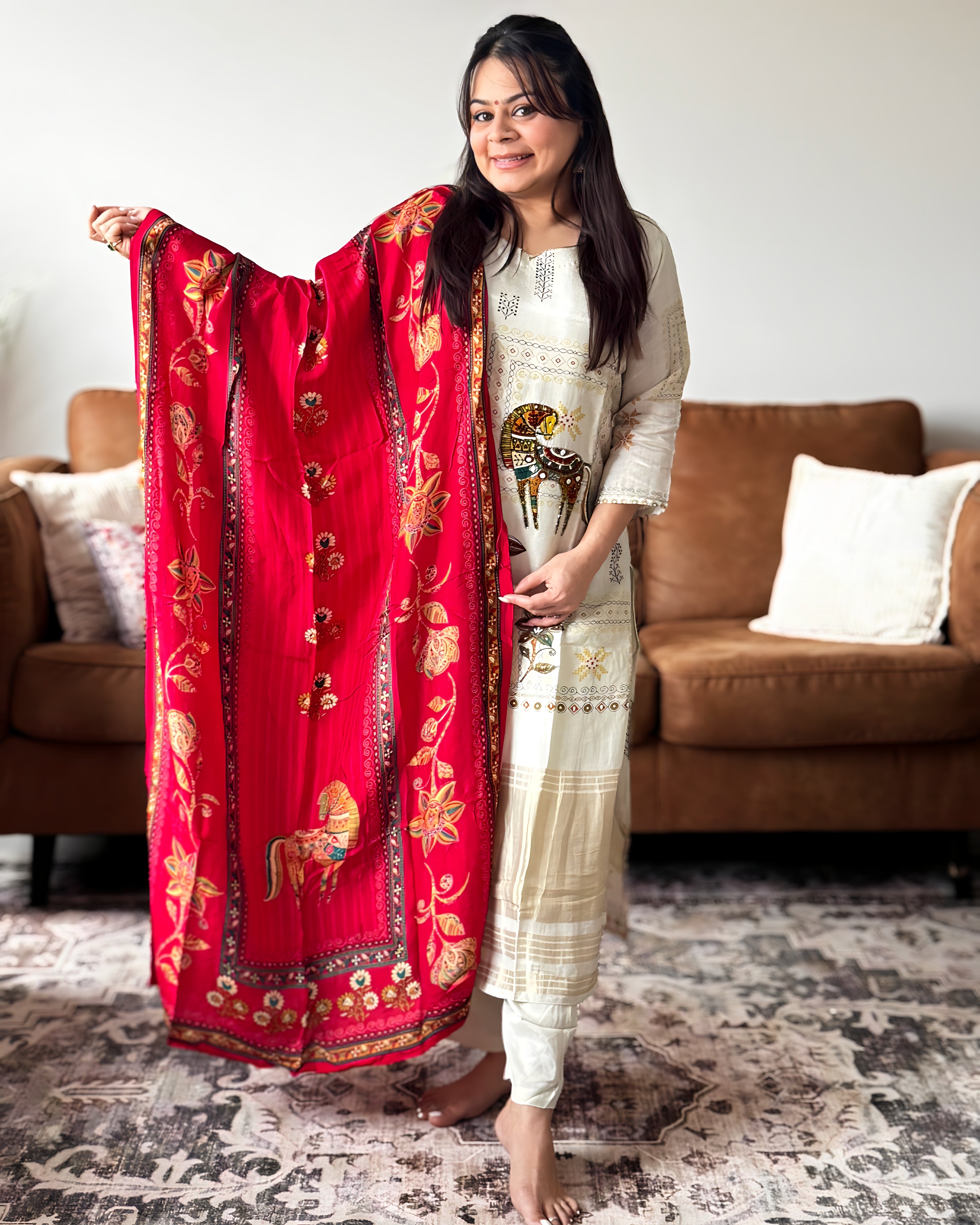 Woman holding a red embroidered dupatta in a living room setting
