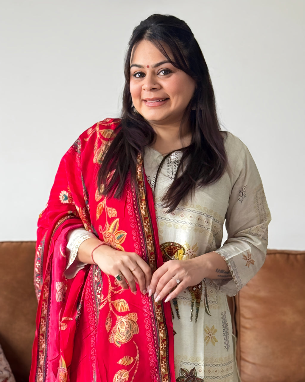 Woman wearing a red and gold traditional scarf with a neutral background