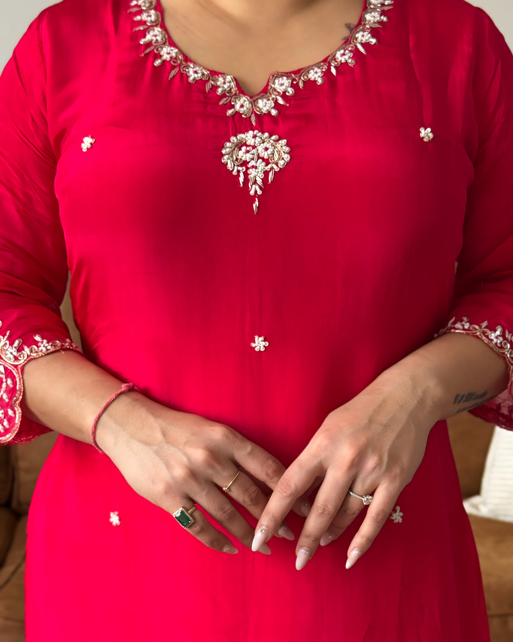 Red traditional outfit with intricate white embroidery on a plain background