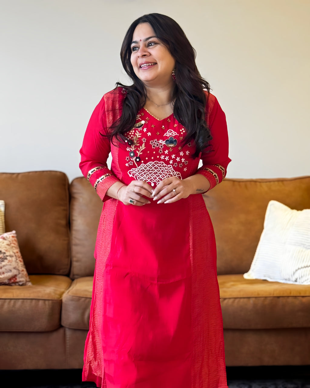 Woman in a red traditional outfit standing in a living room.