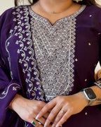 Close-up of a person wearing a purple outfit with intricate white embroidery, showing a watch and ring.