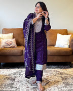 Woman in a purple traditional outfit standing in a living room.