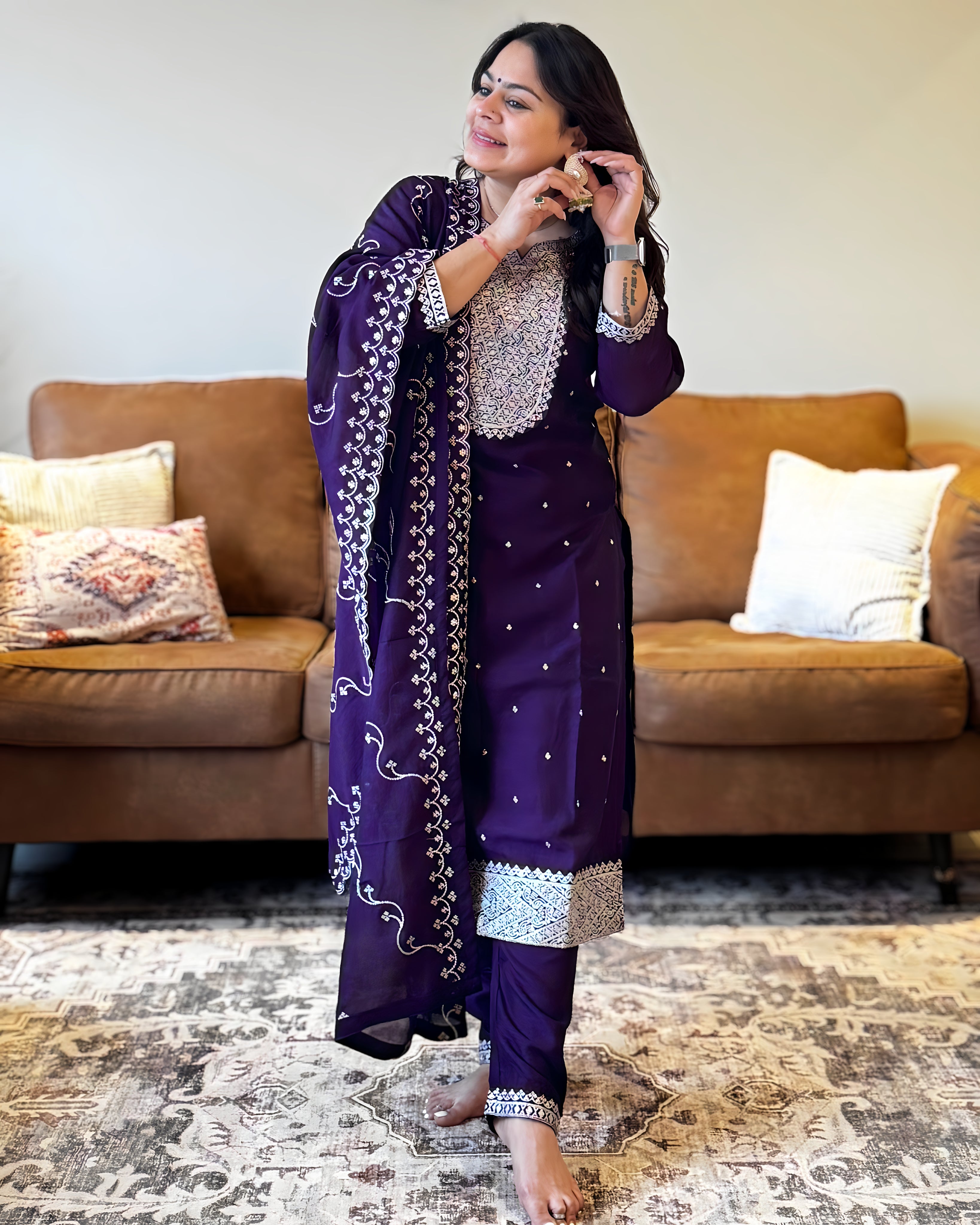 Woman in a purple traditional outfit standing in a living room.