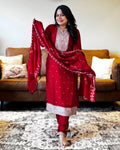 Woman in a red traditional outfit with a matching dupatta in a living room.