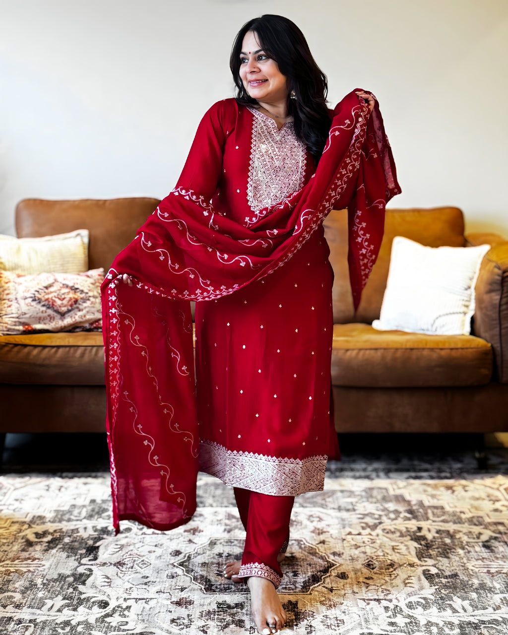 Woman in a red traditional outfit standing in a living room.