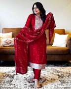 Woman in a red traditional outfit standing in a living room.