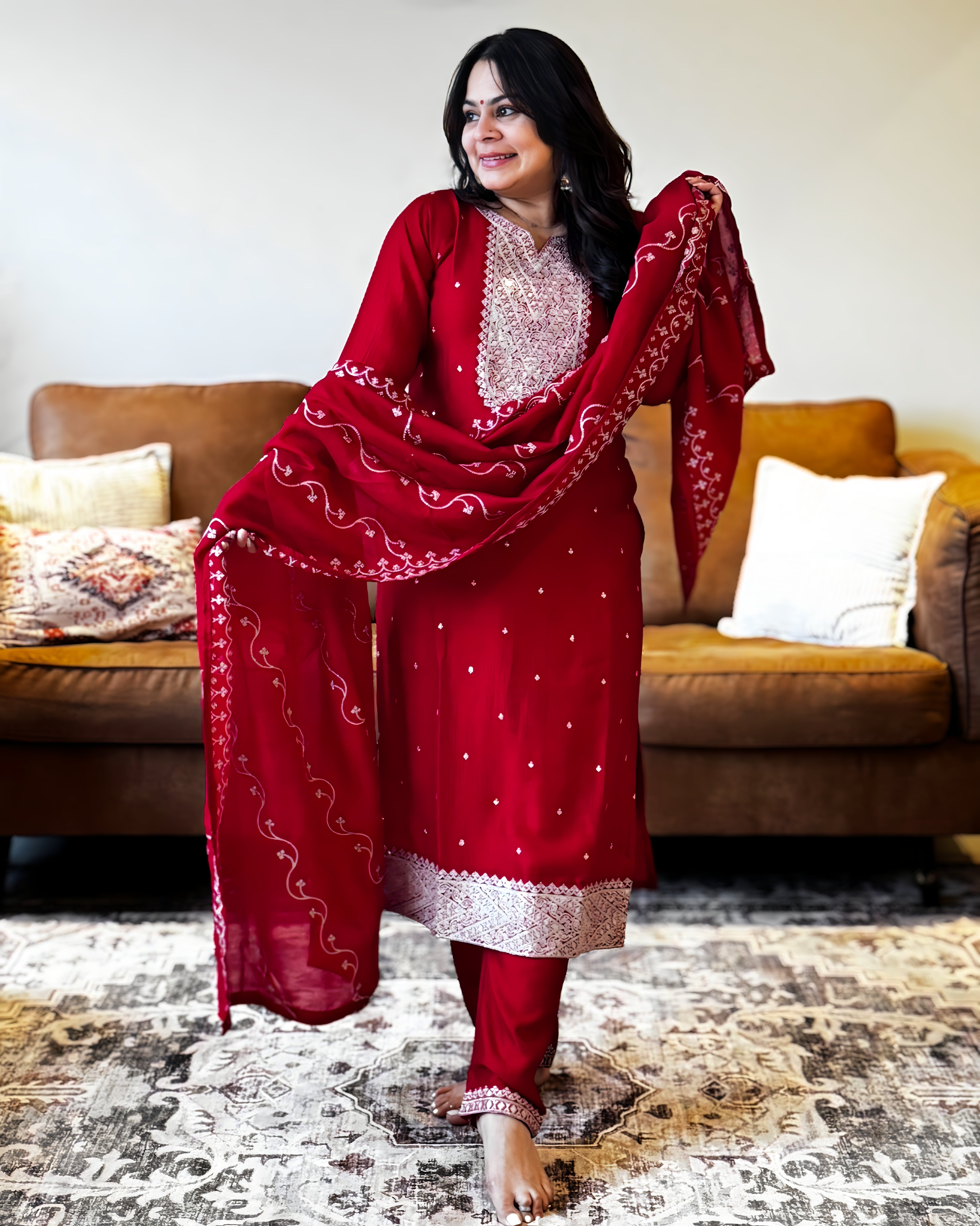 Woman in a red traditional outfit standing in a living room.