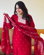 Woman wearing a red traditional outfit with white patterns, holding a matching dupatta.