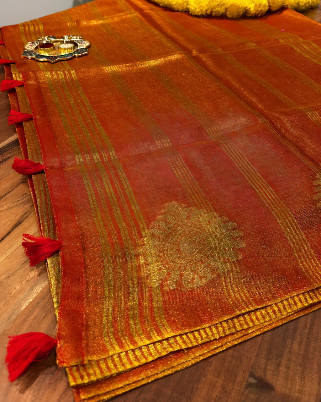 Red and gold traditional fabric with intricate patterns on a wooden surface