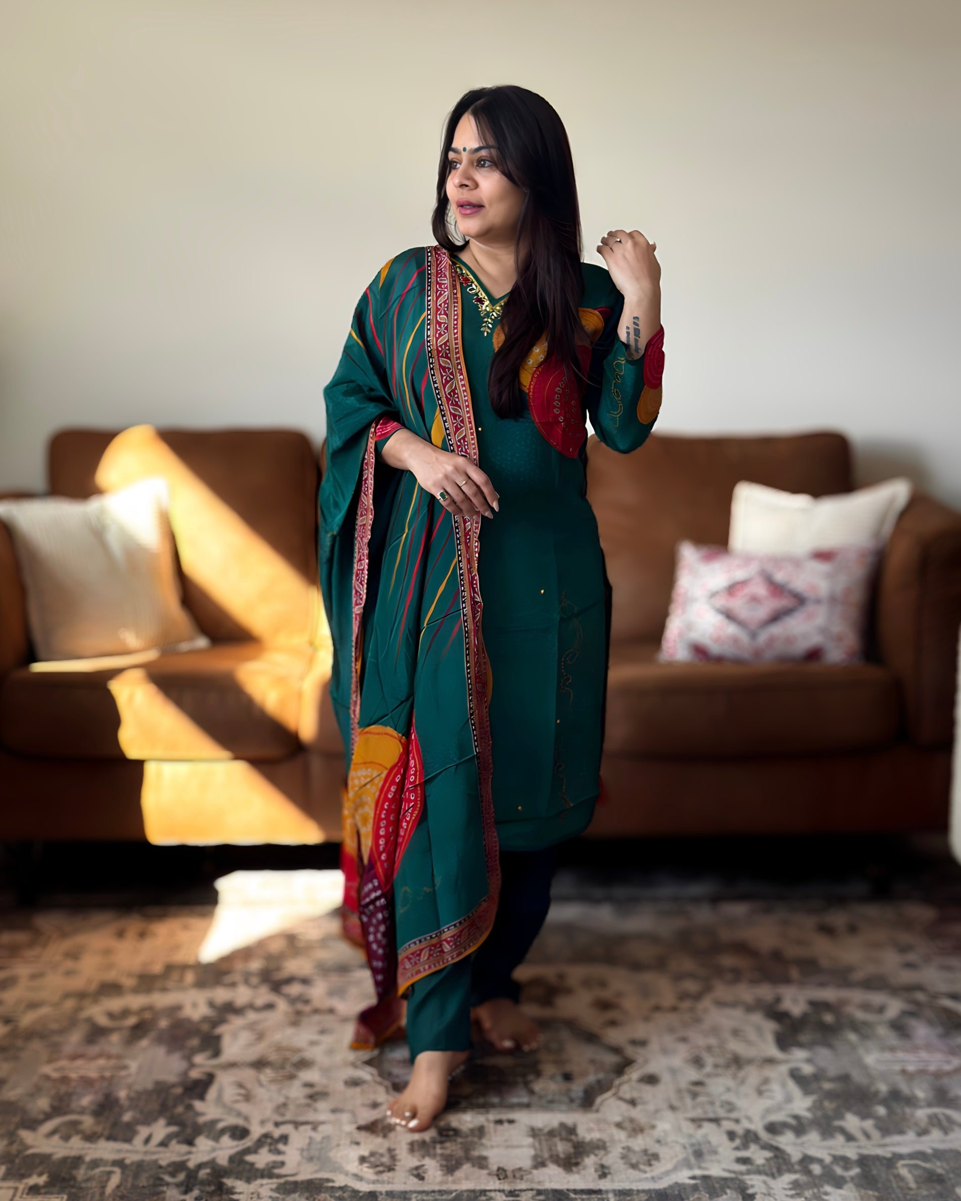 Woman in a green traditional outfit standing in a living room.