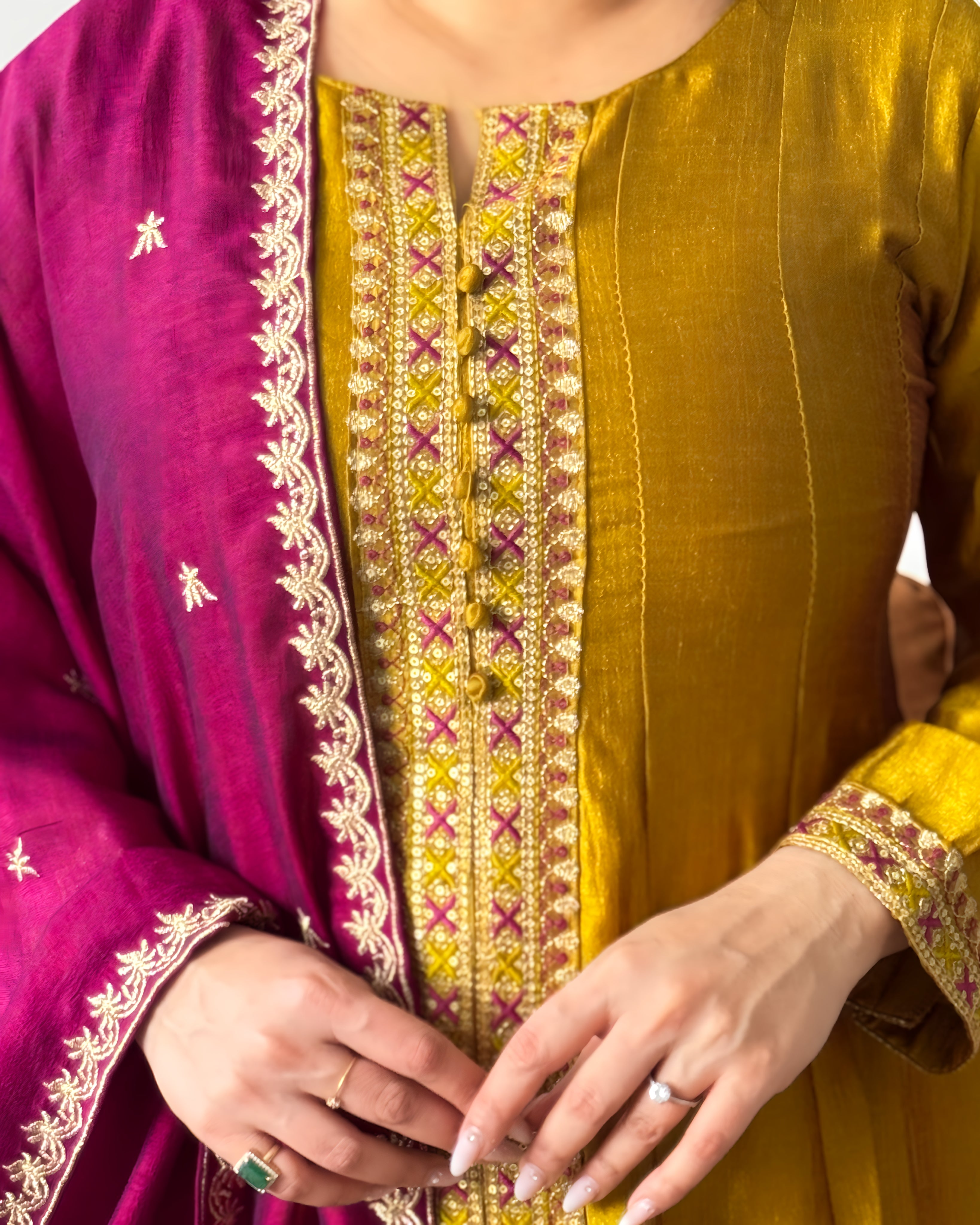 Woman wearing a green traditional outfit with a brown sofa in the background